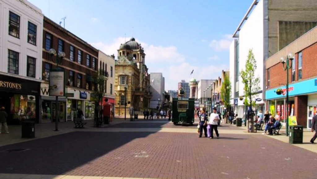 High Road Ilford, East London, featuring shops, supermarkets, and cafes with a vibrant atmosphere.