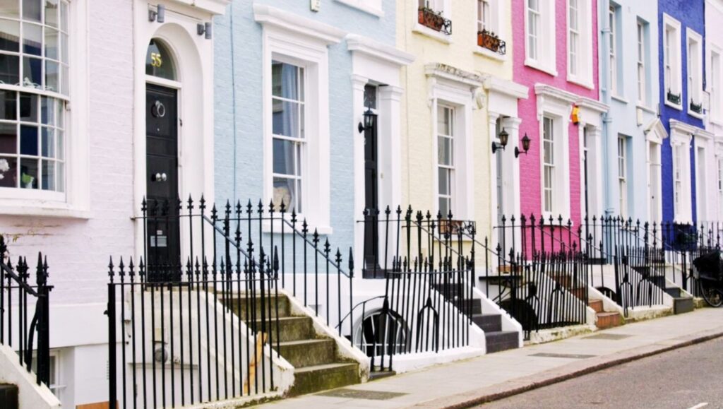A street view of Notting Hill with colorful Victorian townhouses.