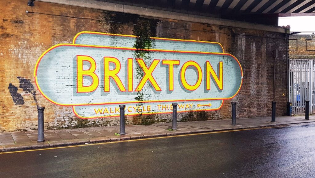 A landlord handing over keys to a tenant in front of a modern Brixton property.